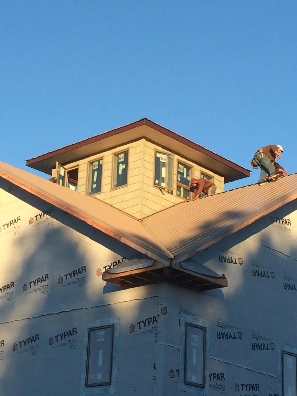 Roofers working around a rooftop cupola on a new metal roof at sunset — Roof Waterproofing in Rutland by Roofing Brothers